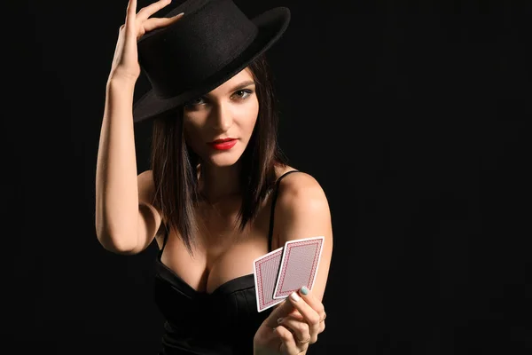 Mulher bonita com cartas de jogar no fundo escuro — Fotografia de Stock