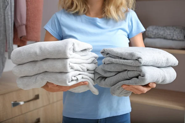 Vrouw met stapels schone kleren thuis, close-up — Stockfoto