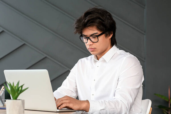 Asian programmer working on laptop in office