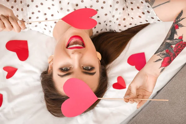 Belle jeune femme au cœur rouge couchée sur le lit. Fête de la Saint-Valentin — Photo