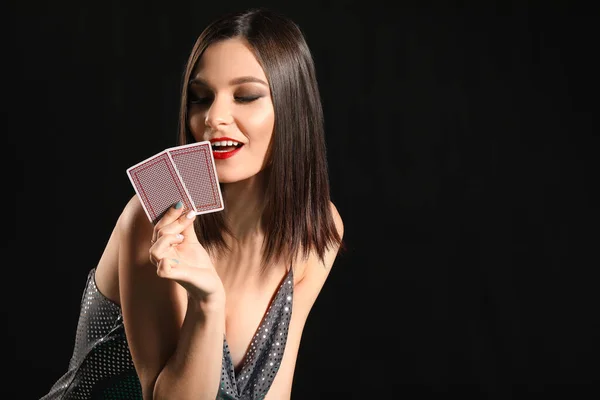 Mulher bonita com cartas de jogar no fundo escuro — Fotografia de Stock