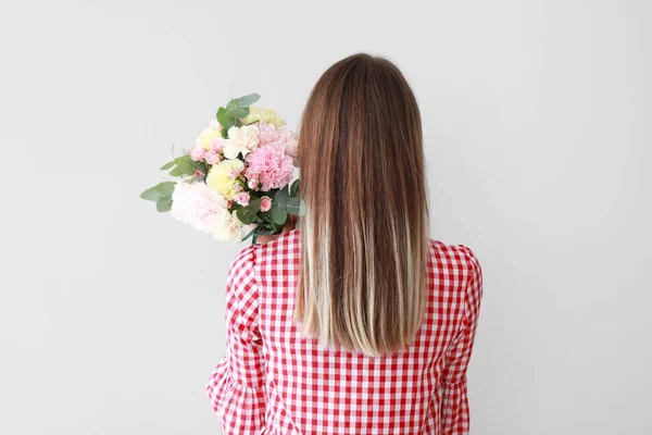 Hermosa joven con ramo de flores de clavel sobre fondo claro —  Fotos de Stock