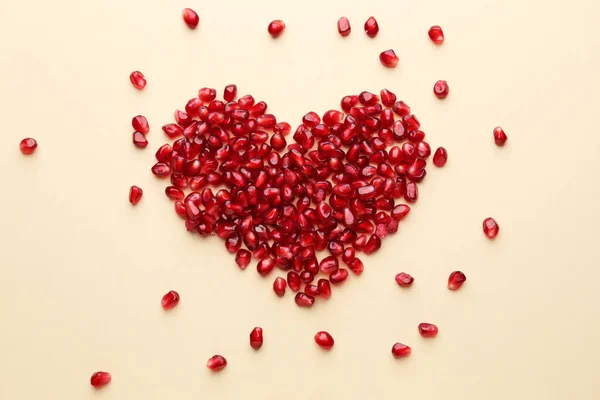 Coeur fait de graines de grenade savoureuses mûres sur fond de couleur — Photo