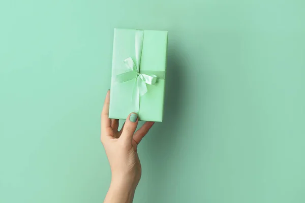 Female hand with turquoise gift box on color background — Stock Photo, Image