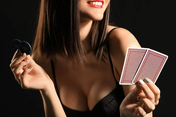 Krásná mladá žena s hracími kartami a hranolky na tmavém pozadí — Stock fotografie