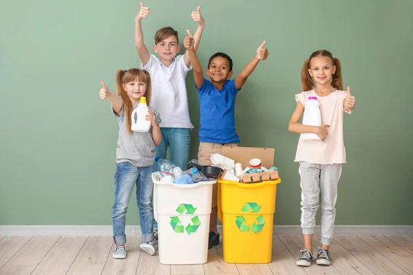 Niños pequeños y contenedores con basura cerca de la pared de color. Concepto de reciclaje —  Fotos de Stock