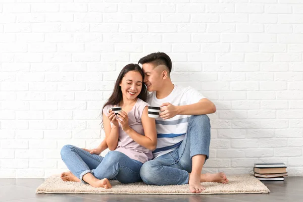 Портрет щасливої молодої азіатської пари п "є каву біля білої цегляної стіни. — стокове фото