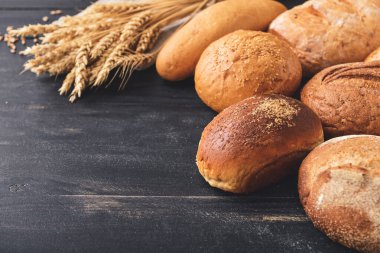 Koyu ahşap masada farklı taze ekmek.