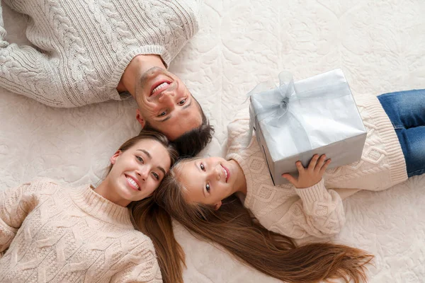 Счастливая молодая семья с рождественским подарком на полу, вид сверху — стоковое фото