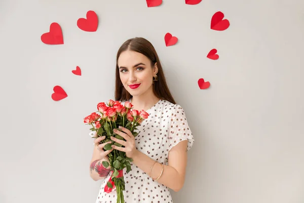 Çiçek buketi ve parlak arka planda kalpleri olan güzel genç bir kadın. Sevgililer Günü kutlaması — Stok fotoğraf