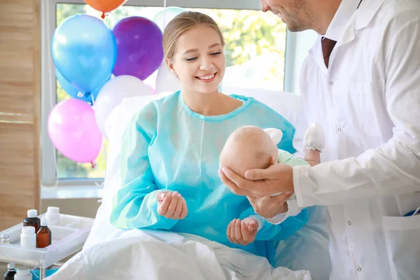 Jonge vrouw met pasgeboren baby en gynaecoloog in kraamkliniek — Stockfoto