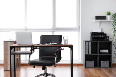 Ofisinde dizüstü bilgisayarı olan modern şık bir iş yeri.