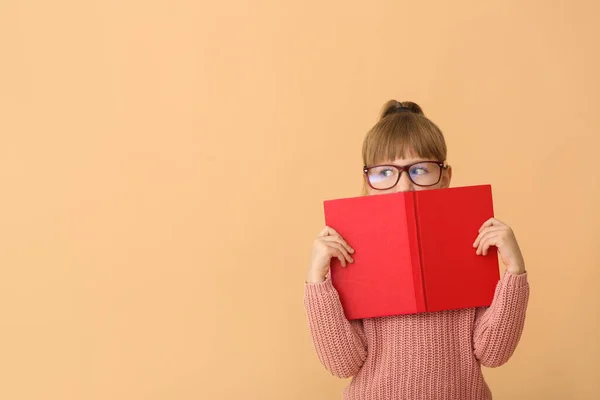 Cute little girl with book on color background — Stock Photo, Image