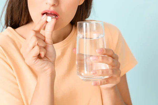 年轻女子服用彩色背景的药物，特写 — 图库照片