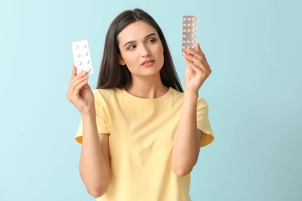 Young woman with pills on color background — Stock Photo, Image