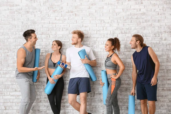 Group of people with yoga mats near brick wall — Stock Photo, Image