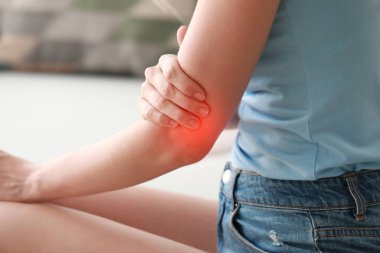 Dirseğindeki ağrıdan muzdarip genç kadın, yakın plan.