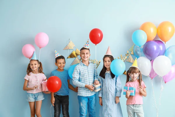 Little children with Birthday gifts and air balloons on color background — Stock Photo, Image