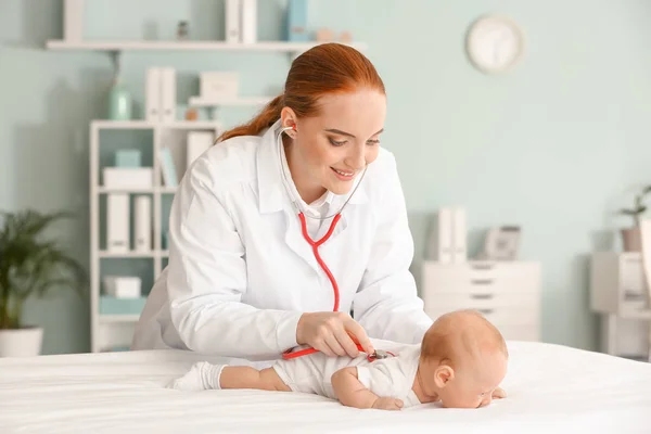 Pediatrician examining cute baby in clinic — Stock Photo, Image