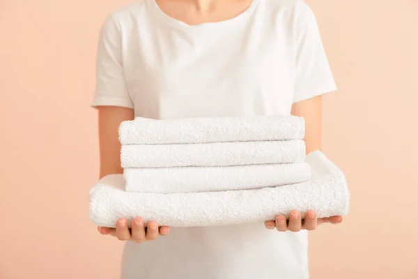 Mulher com toalhas limpas no fundo da cor — Fotografia de Stock
