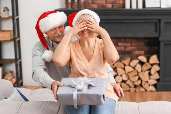 Dojrzały mężczyzna wita swoją żonę prezentem świątecznym w domu — Zdjęcie stockowe