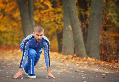 Çömelmiş genç adam parkta pozisyon almaya başla.