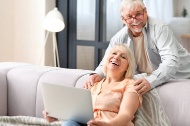 Evde dizüstü bilgisayarı olan olgun bir çift.