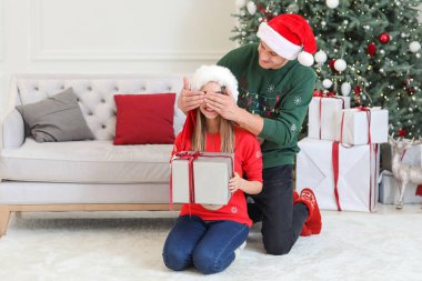 Mutlu genç adam Noel hediyesini evdeki kız arkadaşına veriyor.