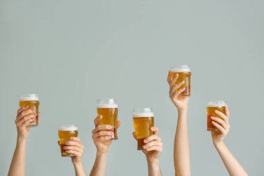 Gri arka planda bira bardakları olan eller
