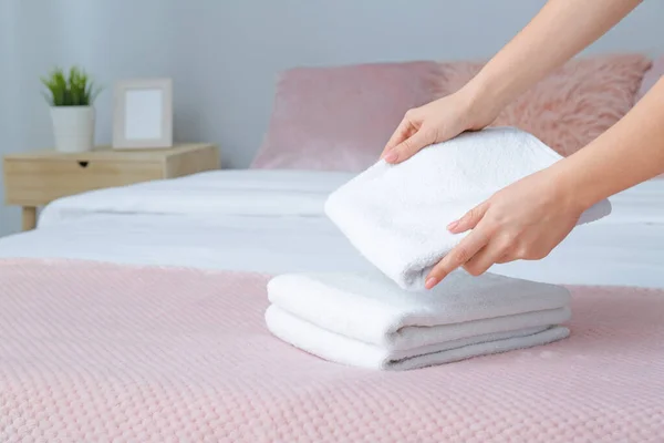 Woman putting clean towels on bed — Stock Photo, Image