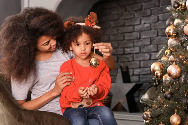 Glückliche afrikanisch-amerikanische Frau und ihre kleine Tochter schmücken den Weihnachtsbaum zu Hause — Stockfoto