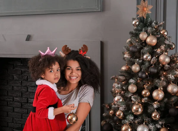 Szczęśliwa Afroamerykanka i jej córeczka blisko pięknej choinki w domu — Zdjęcie stockowe