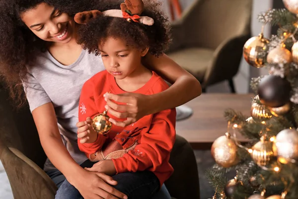 Mulher afro-americana feliz e sua filhinha decorando a árvore de Natal em casa — Fotografia de Stock