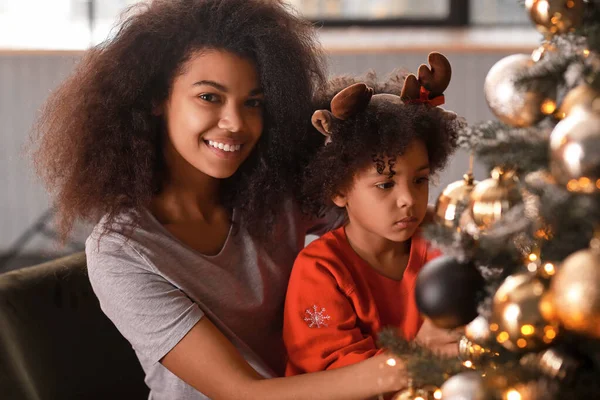 Glückliche afrikanisch-amerikanische Frau und ihre kleine Tochter schmücken den Weihnachtsbaum zu Hause — Stockfoto