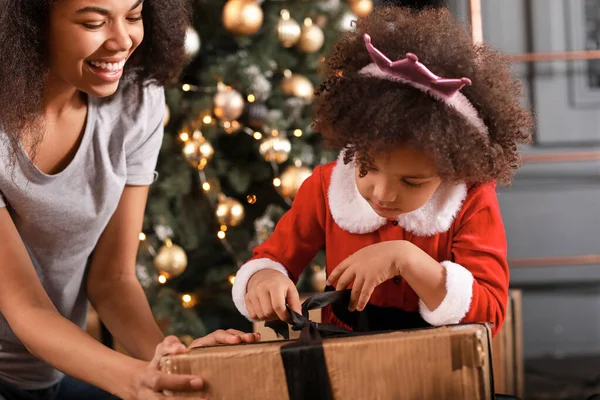 Happy African-American woman and her little daughter opening Christmas gifts at home — Stock Photo, Image