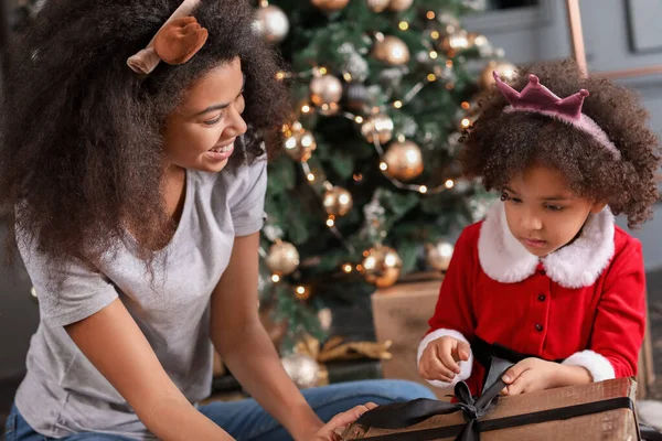 Happy African-American woman and her little daughter opening Christmas gifts at home — Stock Photo, Image