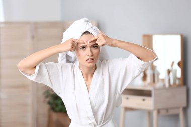 Sivilceleri evde ezen genç bir kadının portresi.