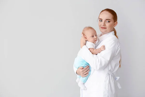 Pediatrician with cute baby on light background — Stock Photo, Image