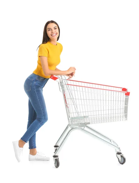 Young woman with empty shopping cart on white background — Stock Photo, Image