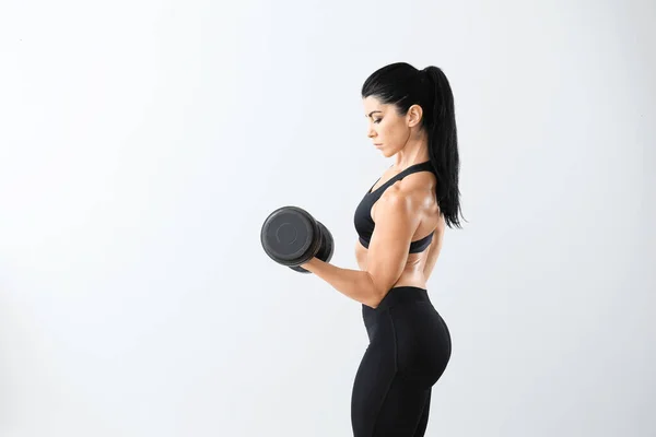 Sporty muscular woman with dumbbell on light background — Stock Photo, Image