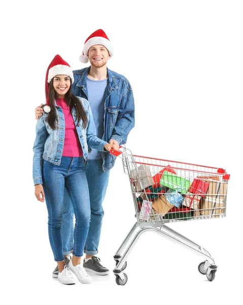 Νεαρό ζευγάρι με καλάθι αγορών γεμάτο χριστουγεννιάτικα δώρα σε λευκό φόντο — Φωτογραφία Αρχείου