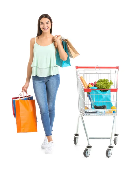 Jonge vrouw met winkelwagentje en tassen op witte achtergrond — Stockfoto