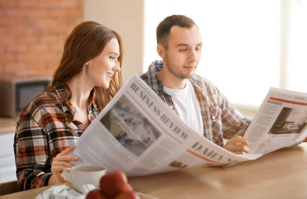 Belo casal jovem lendo jornais na cozinha — Fotografia de Stock