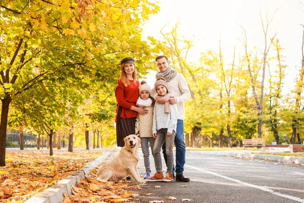 Счастливая семья с собакой в осеннем парке — стоковое фото