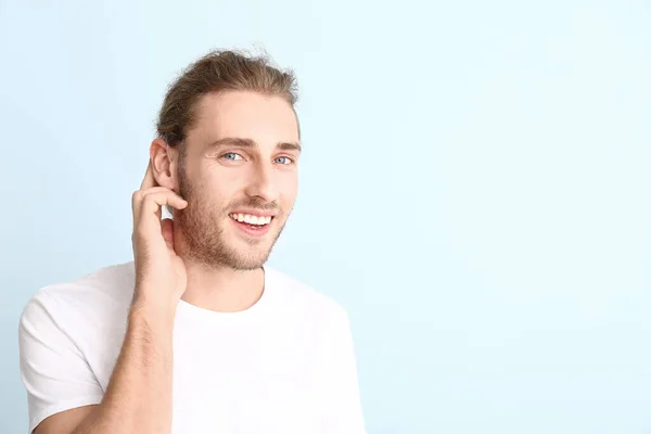 Young man with hearing aid on color background — Stock Photo, Image