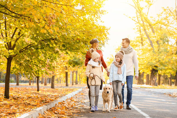 Счастливая семья с собакой, гуляющей в осеннем парке
