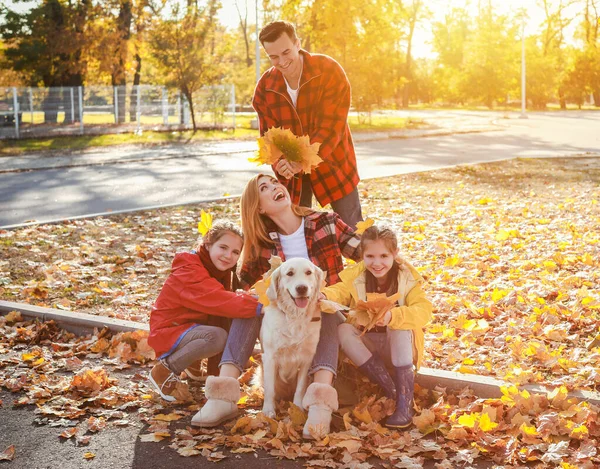 Happy family with dog resting in autumn park — Stock Photo, Image