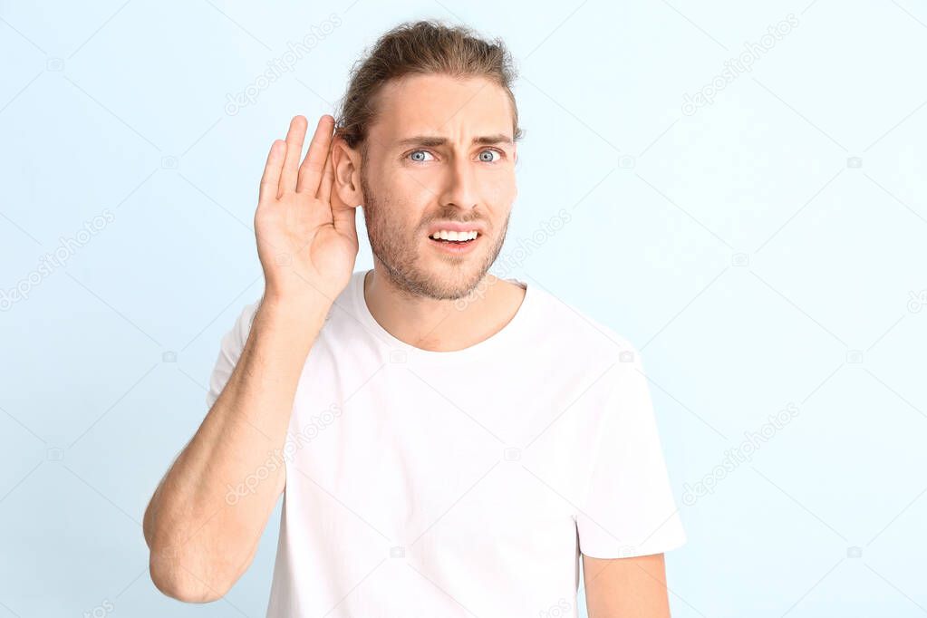 Young man with hearing problem on light background