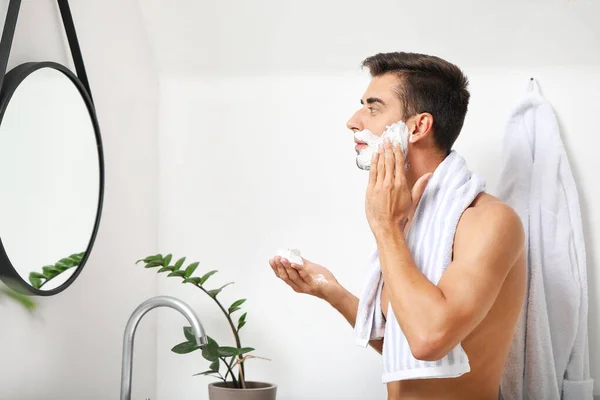 Handsome young man shaving at home — Stock Photo, Image