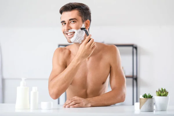 Handsome young man shaving at home — Stock Photo, Image